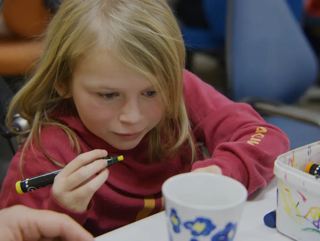 En jente tegner blomster på en kopp. Foto: Erik Lundbye