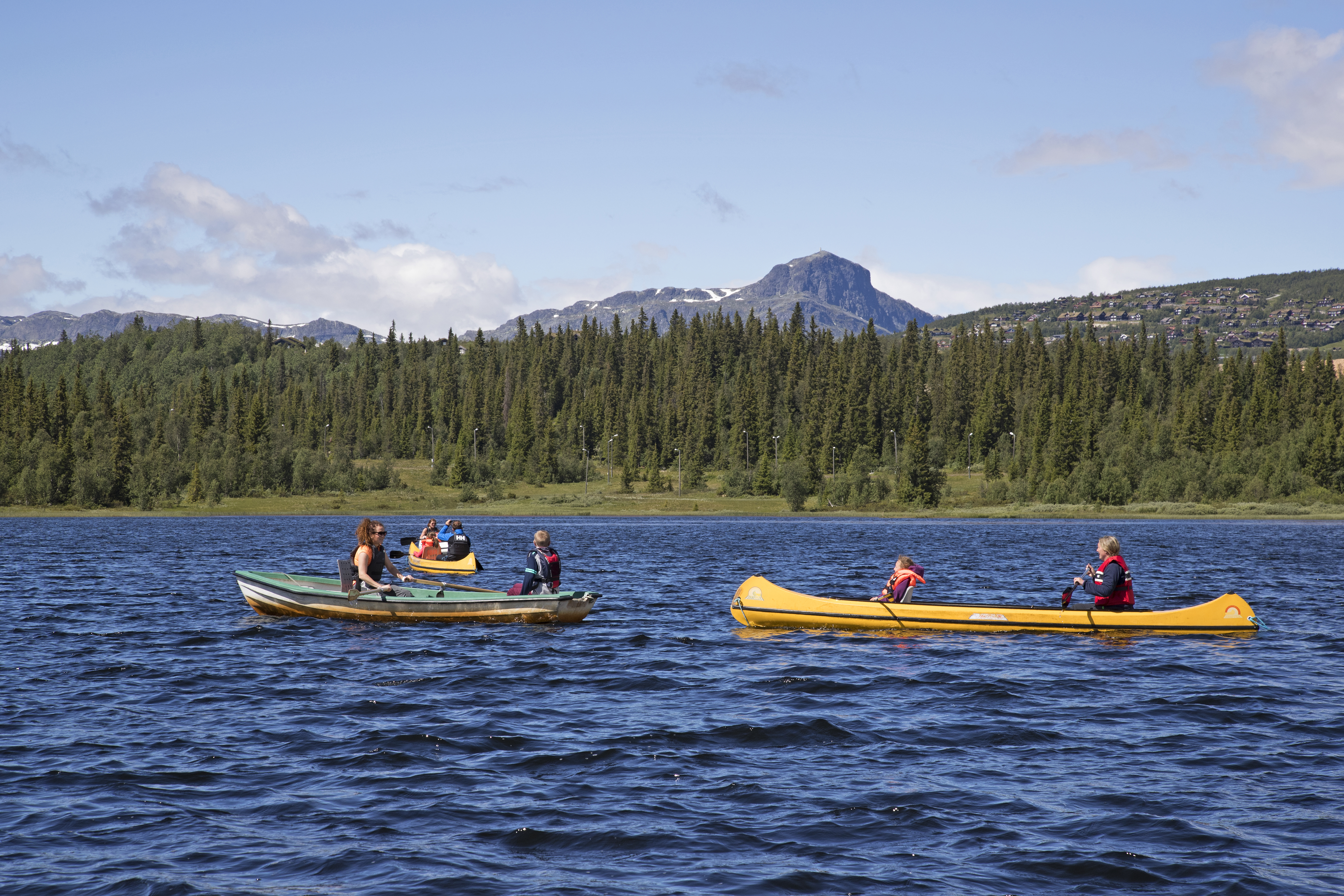To kanoer og en robåt ute på Bamselitjern. Fjellet "Bitihorn" i bakgrunnen. Foto: Thor Østbye