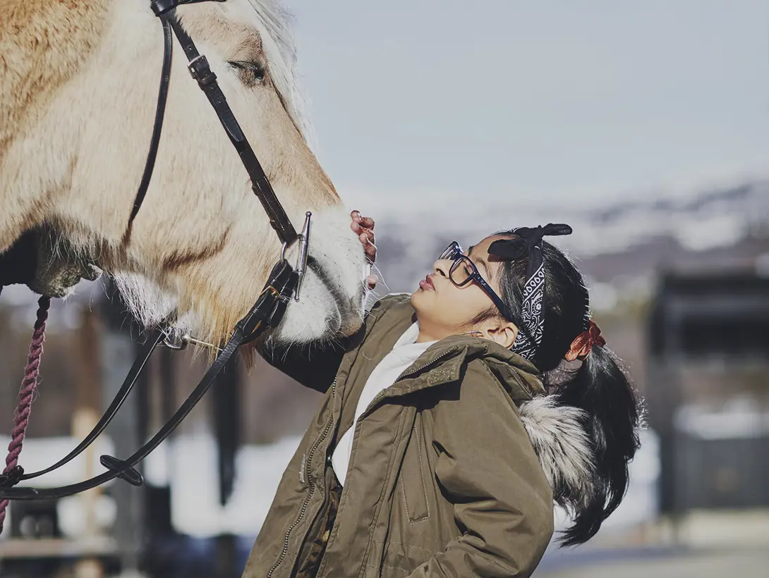 En jente hilser på hesten og klapper den på mulen. Foto: Christine Stokkebryn